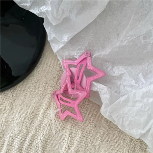 Detailed view of pink glitter star hair clips on soft fabric background for styling