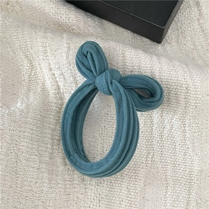 Close-up of teal ribbed fabric bow scrunchie on textured cream textile background