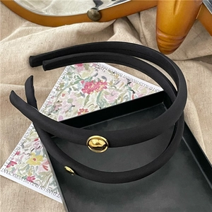Elegant black satin fabric headband set with gold round metal accents on a velvet tray