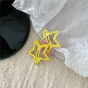 Close-up of yellow glitter star hair clips with hollow design on textured background