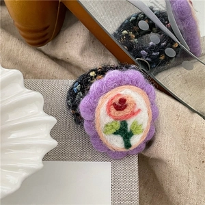 Detailansicht eines handgefertigten Wollfilz-Haargummis mit lila Blüten und Rosenstickerei