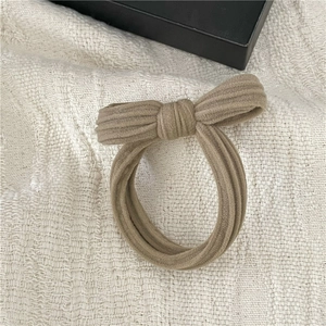Detailed close-up of a beige bow hair scrunchie with soft velvet towel texture on fabric