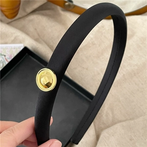 Minimalist black fabric headband with a polished gold metal circular detail