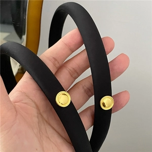 Close-up of black satin-texture headband featuring elegant gold round metal buttons