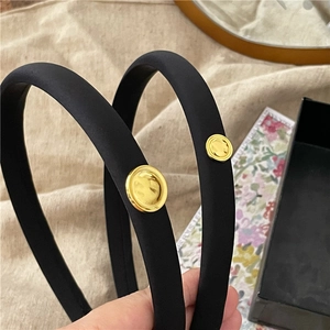 Close-up of black satin padded headband featuring a vintage gold hammer-textured metal disc