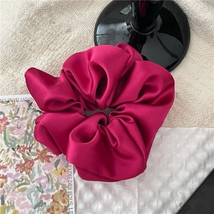 Details der fuchsiafarbenen Satin-Haargummis auf Stoff mit kunstvoller Dekoration