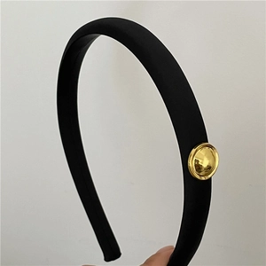Close-up of black satin headband featuring a polished gold round metal plate detail
