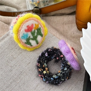 Detail von Wollfilz-Blumen-Haargummis mit Stickerei und kuscheliger Strick-Textur