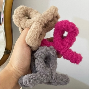 Close-up of three soft teddy plush hair claws in beige, pink, and grey winter colors
