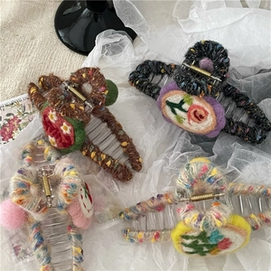 Macro view of colorful knitted wool heart hair claws with floral crochet patterns