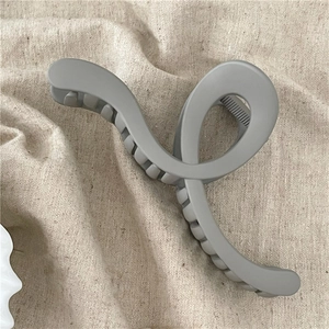 Close-up of a matte grey geometric hair claw clip on soft beige linen fabric texture