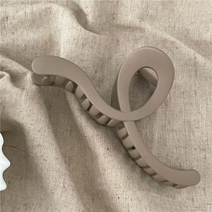 Detail of coffee brown large hair claw clip with matte finish on textured fabric
