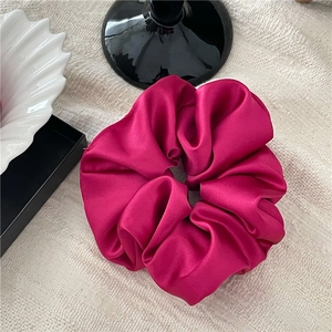 Detail eines drachenfrucht-pinkfarbenen Satin-Haargummis mit sanftem Glanz auf Stoff