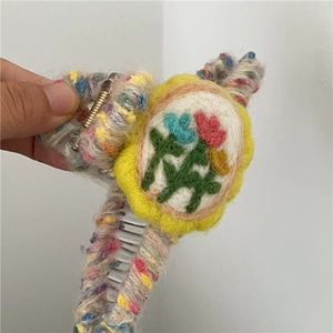 Detailed macro view of colorful knitted hair claw clip with embroidered floral patch