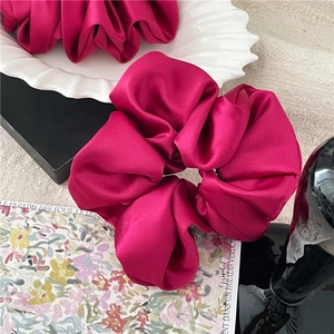 Übergroßer Haargummi aus fuchsiafarbenem Satin auf einem stilvollen Dekoteller