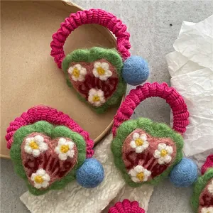 Detailed shot of handmade crochet hair tie with felt heart charm and colorful pompom