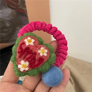 Detailed macro view of handmade wool felt heart hair tie with embroidered floral patterns