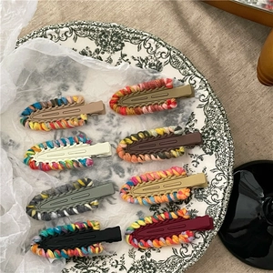 Otto fermagli per capelli colorati in filato intrecciato a mano su un piatto decorativo