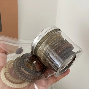 Macro view of spiral telephone cord hair ties in earthy tones within a clear jar