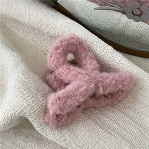 Close-up of pink plush hair claw clip with soft faux fur texture and golden metal spring