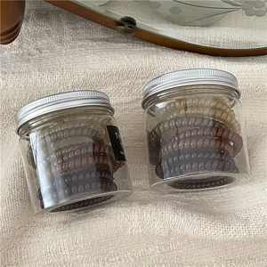 Close-up of coffee-toned spiral hair ties in transparent jars with silver metal lids