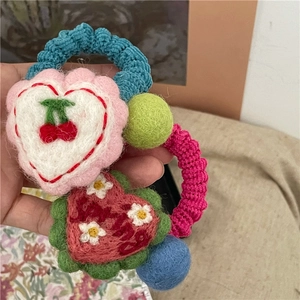 Detail of handmade wool felt hair tie with crochet loops, colorful hearts, and cherry embroidery