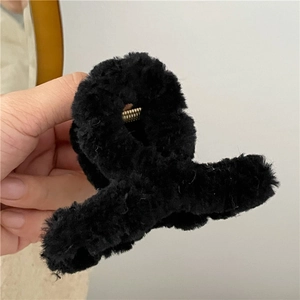 Detail of soft black plush hair claw clip with golden metal spring for winter styling
