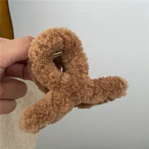 Close-up of brown plush hair claw clip with golden metal spring and soft fleece texture