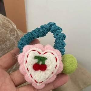 Detail of wool felt heart hair tie with cherry embroidery and soft green pompom