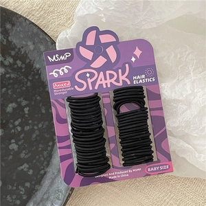 Close-up of baby size black hair elastics on purple card with premium textured backdrop