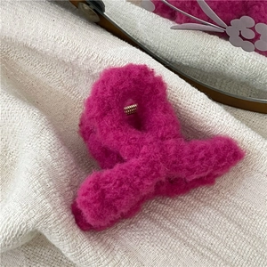 Macro shot of hot pink plush faux fur claw clip on a white knit background texture