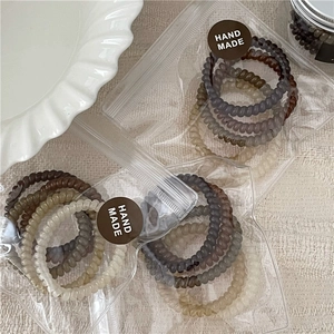 Close-up of earth-toned jelly spiral hair ties in transparent packaging with seal