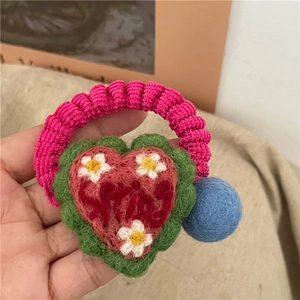 Detail of cute handmade felt heart hair tie with colorful wool balls and embroidery