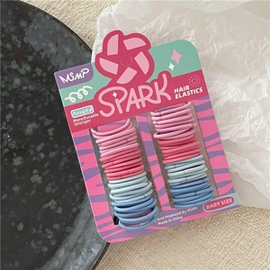 Close-up of pink and blue baby elastic hair bands on a minimalist textured tray
