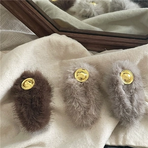 Plush faux fur hair clips with gold metal emblems in chocolate brown and beige tones