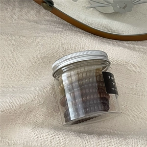 Neutral earth tone spiral hair ties stored in a transparent jar with silver lid