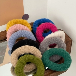 Colorful plush scrunchies in various soft cream shades stacked on a wooden table