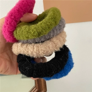 Colorful plush hair scrunchies in six vibrant colors held by hand for cozy winter hairstyles