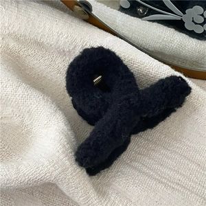 Detail of soft black plush hair claw clip with metal spring on knit background