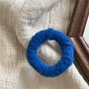 Detailed view of fluffy bright blue plush hair scrunchie with soft knit texture