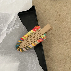 Dettaglio macro di un fermaglio per capelli in lana intrecciata a mano multicolore