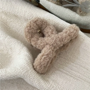 Detail showing the soft cream-colored plush texture and metal spring of this hair claw clip