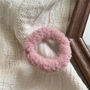 Close-up of soft pink plush hair scrunchie with fluffy texture and elastic band