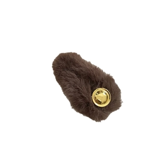 Luxurious faux mink fur hair clip with golden round metallic emblem in deep brown color