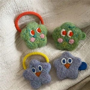 Detail of wool felt star and flower hair clips with cute cartoon eyes on white fabric