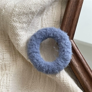 Detail view of Morandi blue plush scrunchie on soft cream waffle fabric texture