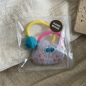 Detail of wool felt cloud hair ties with blue eyes in a transparent zipper pouch