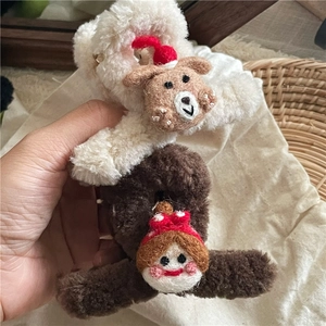 Détail de pinces à cheveux en peluche avec un ours blanc et une poupée brune à chapeaux rouges