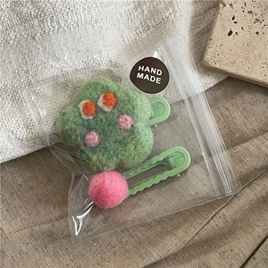 Detailed set of two handmade wool felt hair clips in green and pink in a clear bag