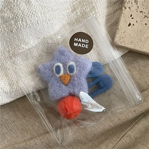 Close-up of handmade purple star and red wool felt hair clip set in packaging